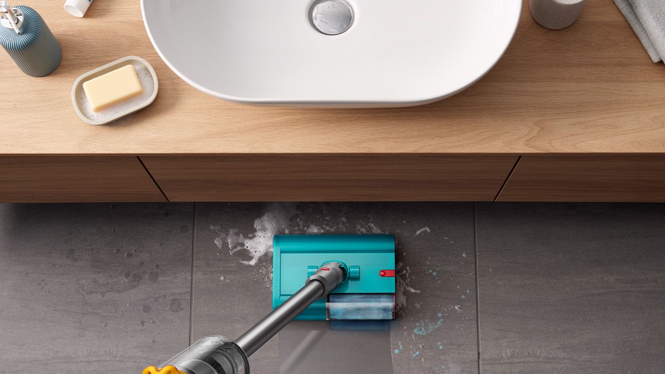 La brosse lavante en train de nettoyer le sol carrel&eacute; d&rsquo;une salle de bain.