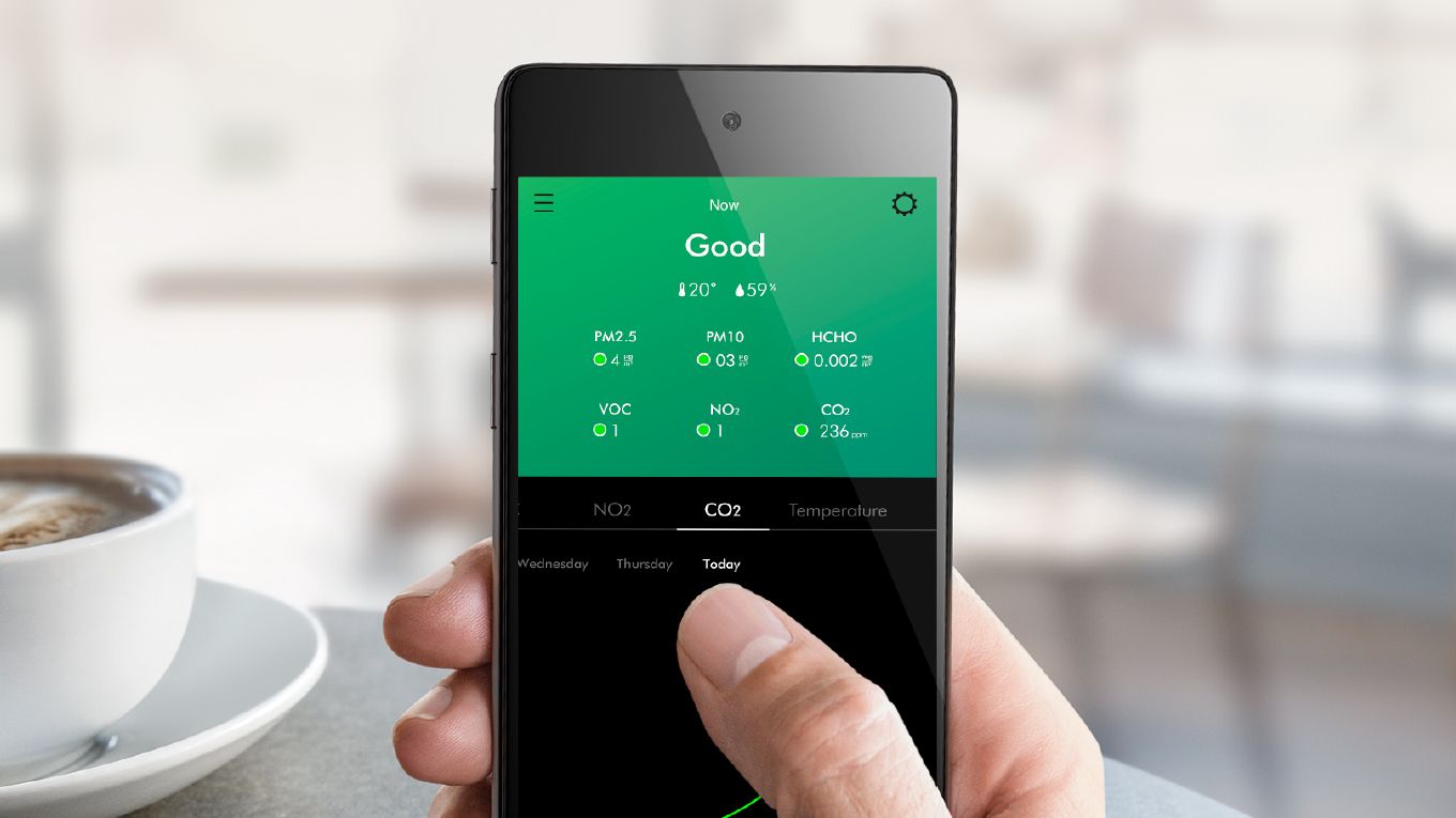 Gros plan d&rsquo;une main tenant un t&eacute;l&eacute;phone intelligent, l&rsquo;&eacute;cran affichant les concentrations de polluants dans le logement. 